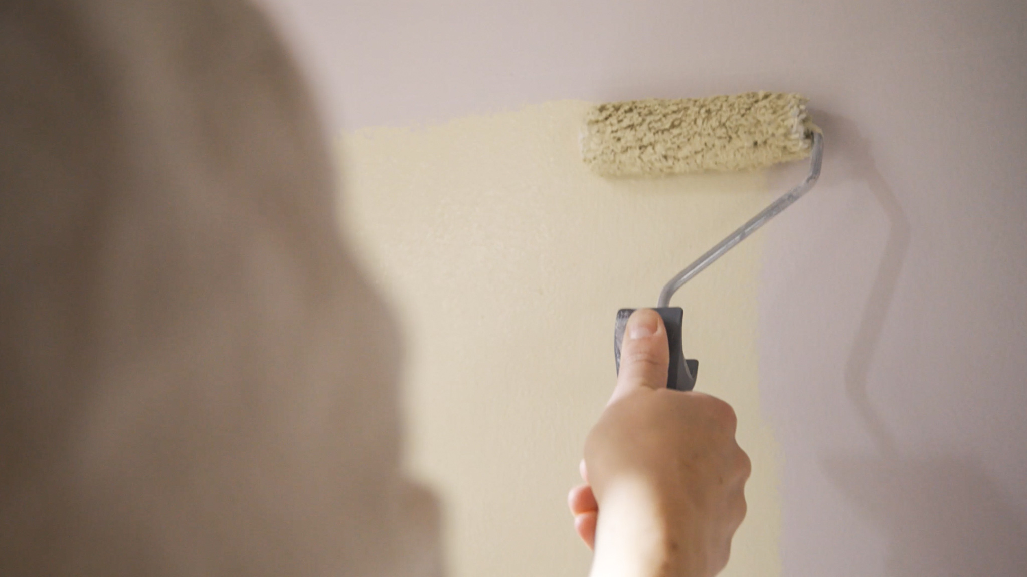 使用滚筒刷在墙面上涂刷大漠驼铃色彩