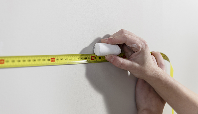 在墙面使用卷尺和粉笔做标记