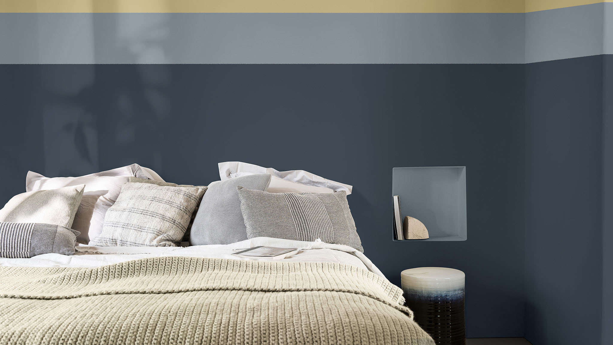 在大面积深蓝色墙面上方搭配浅色线条的卧室